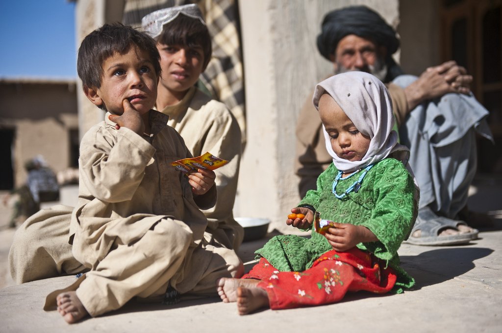Bambini afghani giocano per terra.
